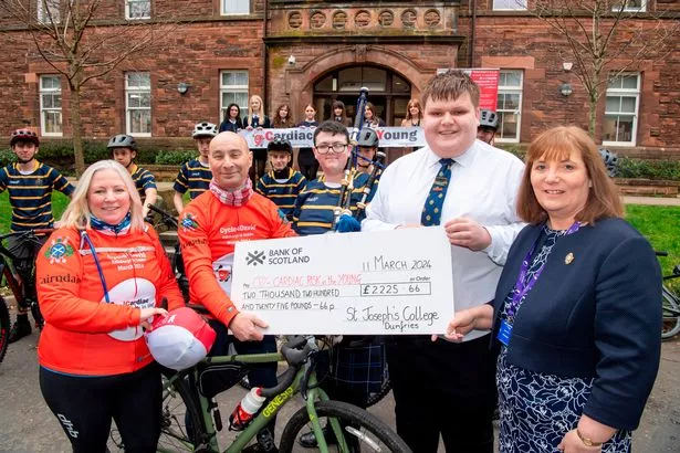Pupil Matthew Reid and head teacher Bernadette Jones hand over a cheque to the Hills, with piper James Gray looking on